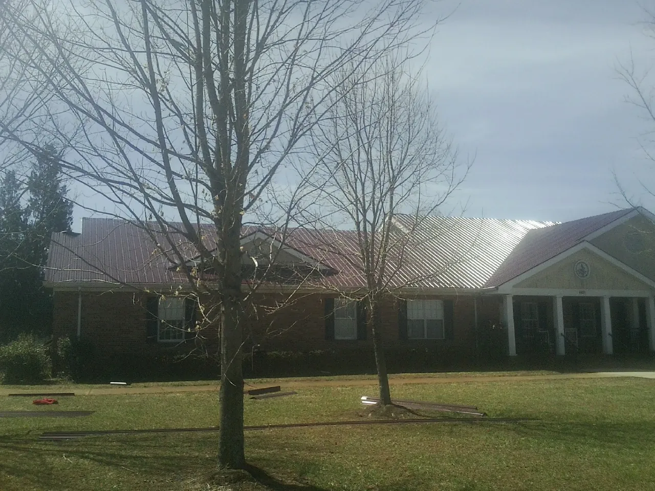 Red metal roof on a brick building seen from the front lawn in Porter Ranch