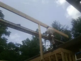 Carpenter setting a ridge beam over a new addition frame — Ice Dam Removal by Roofing Brothers in Porter Ranch