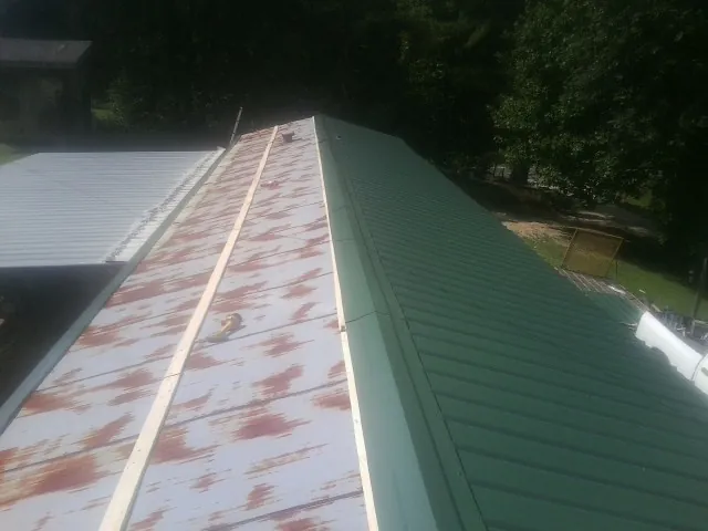 Old rusted panels beside newly installed green metal roofing — Wind Damage Roof Repair by Roofing Brothers in Porter Ranch