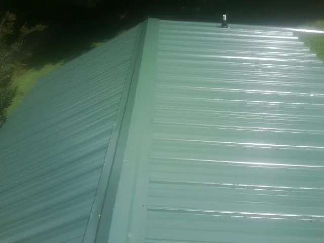 New green metal panels meeting at the ridge of a roof — Flat Roof Repair work by our crew in Porter Ranch