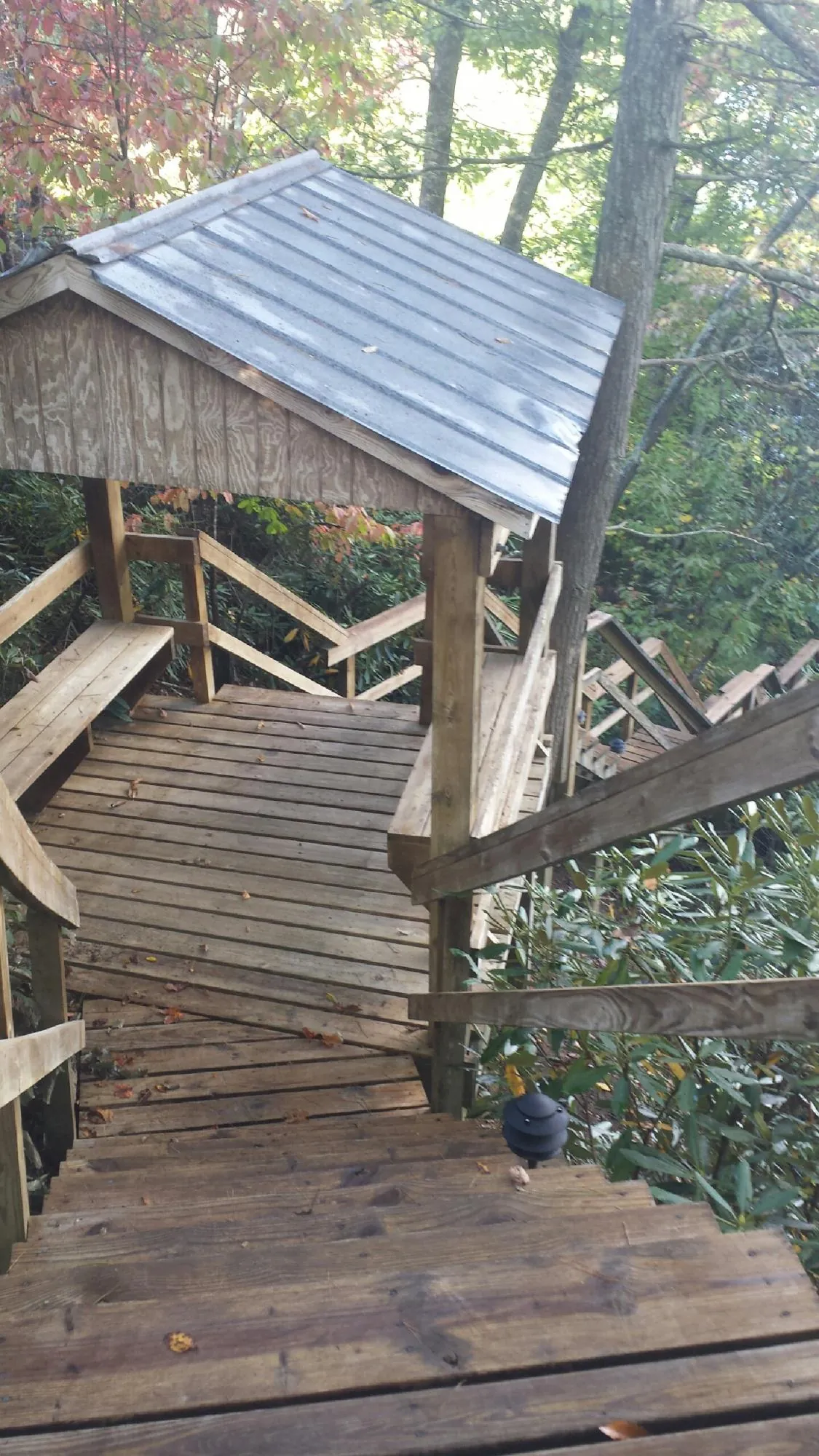 Metal roofed shelter over wooden steps on a wooded walkway — Skylight Repair & Installation work by our crew in Porter Ranch