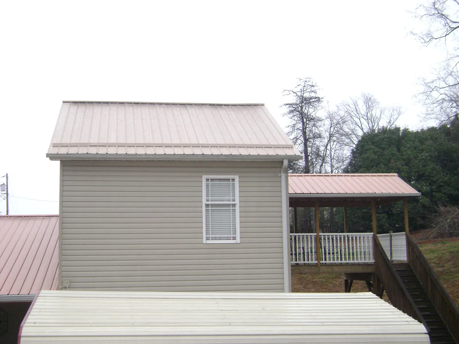 Tan metal roofs on a two story addition and attached porch, from a Roof Replacement job in Porter Ranch