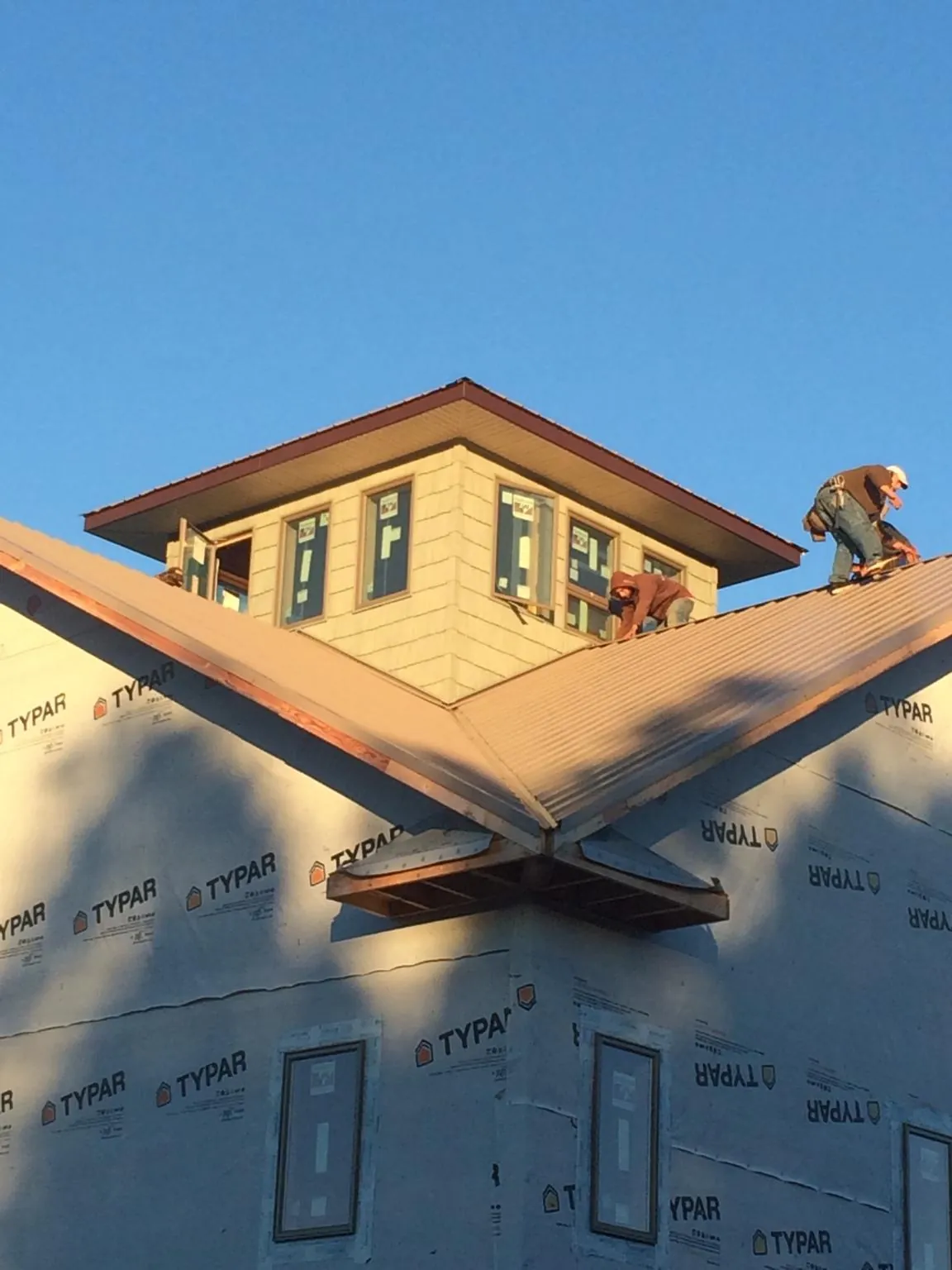 Roofers working around a rooftop cupola on a new metal roof at sunset — Roof Waterproofing in Porter Ranch by Roofing Brothers